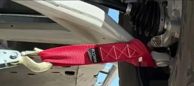 Red tow strap attached to a vehicle's tow hook.