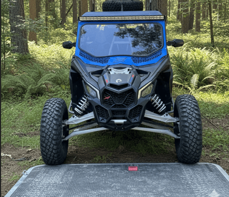 A blue all-terrain vehicle parked on a forest path.
