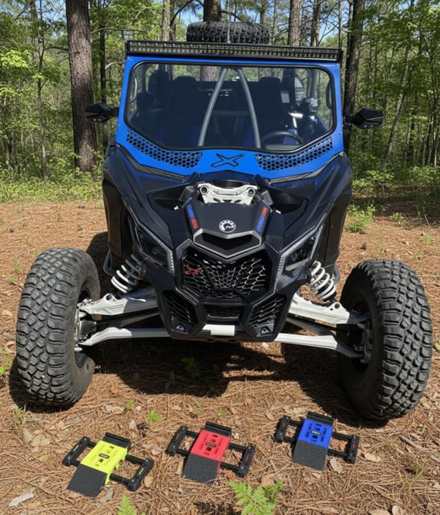Blue off-road vehicle with large tires parked in a forest clearing.